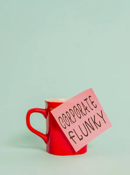 Textschild, das korporative Flunkerei zeigt. konzeptionelles Foto jemand, der gehorsam für einen anderen demonstriert in Gesellschaft Kaffeebecher Tasse farbige klebrige Note liegt schön pastellfarbenen Hintergrund. — Stockfoto