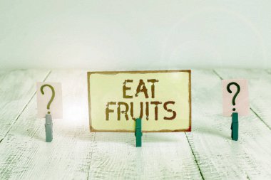 Ye Meyveleri 'ni gösteren bir mesaj. Kavramsal fotoğraf, huanalysiss ya da hayvanlar için kullanışlı bitki yetiştirme ürünlerini tüketir. Tahta masaya yapıştırılmış ataçlarla karalanmış ve ufalanan çarşaf..