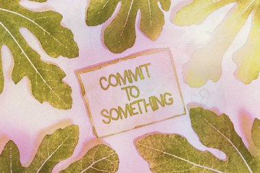 Writing note showing Commit To Something. Business photo showcasing To Live a Life of Purpose with Pride Honor a Promise Leaves surrounding notepaper above empty soft pastel table.