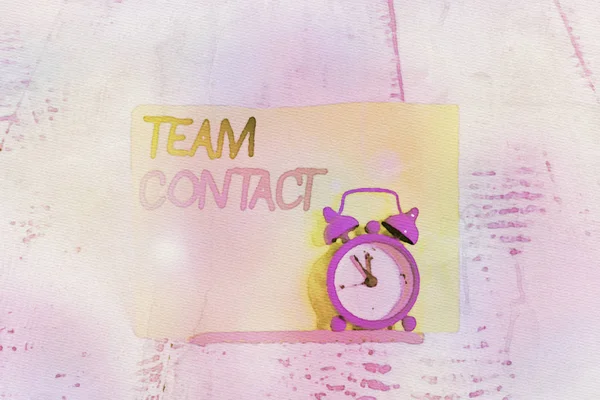 Text schreiben Teamkontakt. Businesskonzept für das Zusammenspiel der Einzelpersonen in einem Team oder einer Gruppe Mini-blauer Wecker stehen gekippt über Pufferdraht vor Notizblock. — Stockfoto