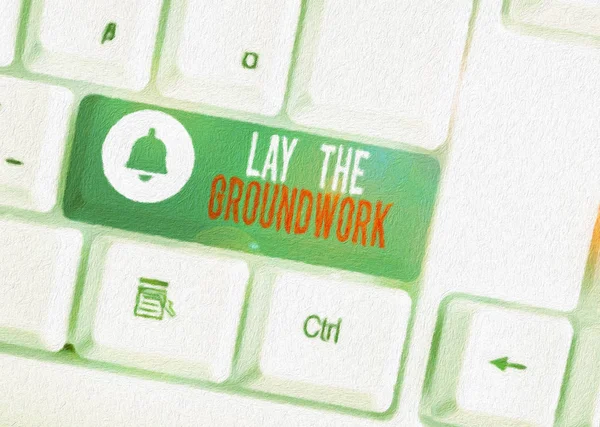 Text sign showing Lay The Groundwork. Conceptual photo Preparing the Basics or Foundation for something White pc keyboard with empty note paper above white background key copy space.