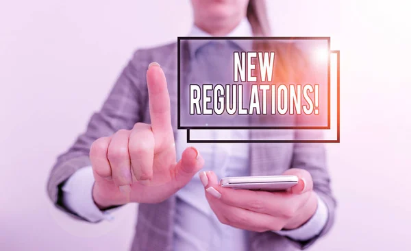 Text sign showing New Regulations. Conceptual photo rules made government order control something done Business concept with mobile phone and business woman. — Stock Photo, Image