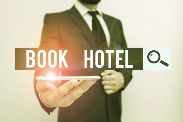 Handwriting text Book Hotel. Concept meaning an arrangement you make to have a hotel room or accommodation Male human wear formal work suit hold smart hi tech smartphone use one hand. — Stock Photo, Image