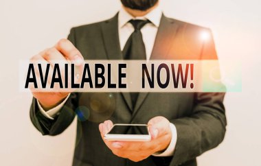 Şimdi kullanılabilir olduğunu gösteren metin işareti. Kavramsal fotoğraf, şu anda elde edilebilir ya da kullanılabilir. Şu anda erkek insan kıyafeti giyiyor. Akıllı, yüksek teknoloji akıllı telefon kullan..