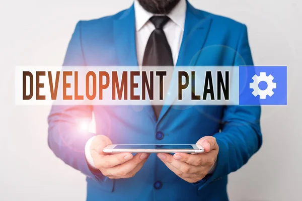 Text sign showing Development Plan. Conceptual photo the planning of the development of an area of land Businessman in blue suite with a tie holds lap top in hands.