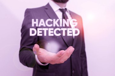 Hacking 'in tespit edildiğini gösteren kavramsal el yazısı. İş fotoğrafı metni verinin varlığını veya izinsiz erişimini tanımlar. Sakallı bir erkek resmi işçi kıyafeti giyer..