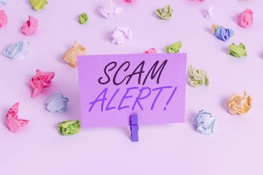 El yazısı yazıları Scam Alert. Kurbana inandırarak sahte para kazanmak anlamına gelen kavram. Renkli buruşmuş kağıtlar boş hatırlatıcı beyaz zemin çamaşır mandalı..