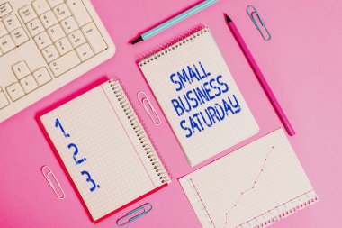 Handwriting text writing Small Business Saturday. Concept meaning American shopping holiday held during the Saturday Writing equipments and computer stuffs placed above colored plain table.