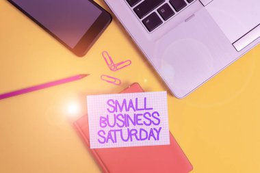 Conceptual hand writing showing Small Business Saturday. Business photo showcasing American shopping holiday held during the Saturday Laptop smartphone clip pencil paper sheet colored background.
