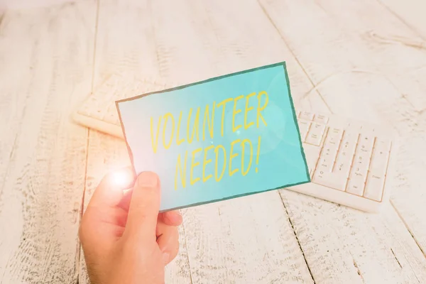 Writing note showing Volunteer Needed. Business photo showcasing asking demonstrating to work for organization without being paid Man holding colorful reminder square shaped paper wood floor. — Stock Photo, Image