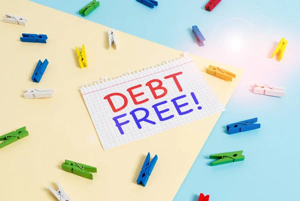 Handwriting text Debt Free. Concept meaning does not owning any money or things to any individual or companies Colored clothespin paper empty reminder yellow blue floor background office.