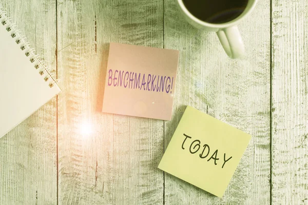 Text sign showing Benchmarking. Conceptual photo evaluate something by comparison with standard or scores Stationary placed next to a cup of black coffee above the wooden table. — Stock Photo, Image