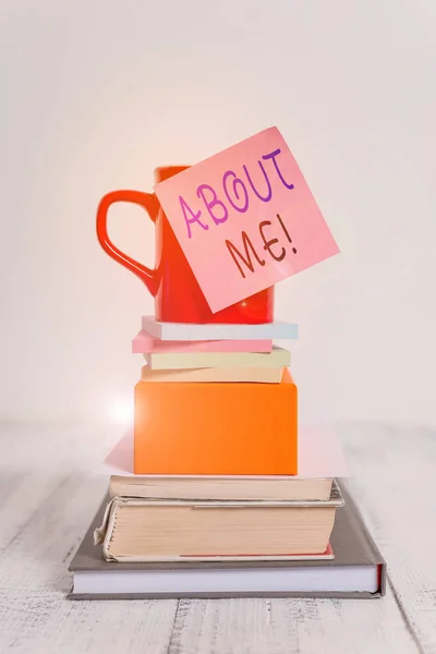 Conceptual hand writing showing About Me. Business photo showcasing telling someone list of your good and bad properties Cup sticky note stacked note pads books box wooden table.