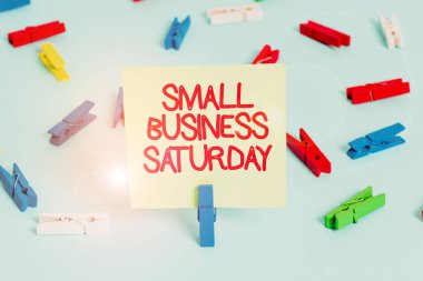 Word writing text Small Business Saturday. Business concept for American shopping holiday held during the Saturday Colored clothespin papers empty reminder blue floor background office pin.