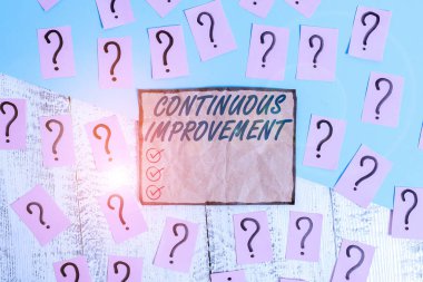 Sürekli Gelişme gösteren bir not yazıyorum. Ürün ve işlemleri geliştirmek için devam eden bir iş fotoğrafı. Ahşap masanın üzerinde kalın kartonla yazılmış ve parçalanmış kağıtlar..