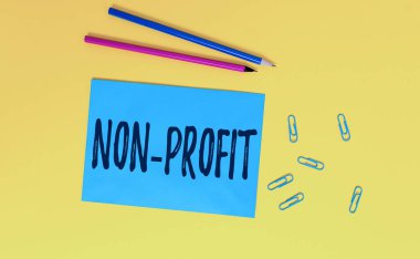 Non Profit 'i gösteren kavramsal el yazısı. İş fotoğrafı metni öncelikli olarak kâr kuruluşu için yapılmadı veya yürütülmedi. Boş kağıt kağıdı iletisi anımsatıcı kalemler ataç renkli arkaplan.
