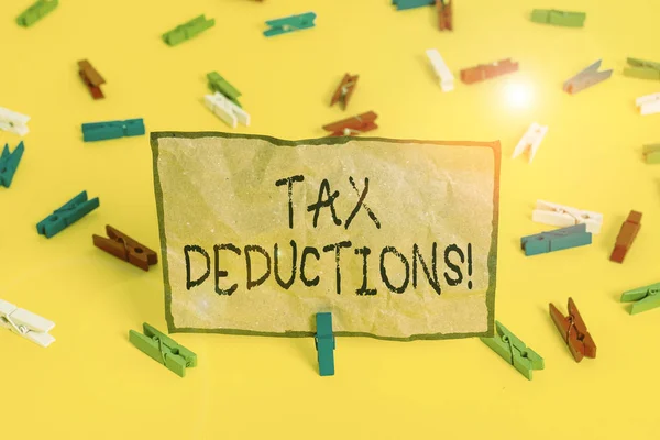 Handwriting text writing Tax Deductions. Concept meaning reduction income that is able to be taxed of expenses Colored clothespin papers empty reminder yellow floor background office. — ストック写真