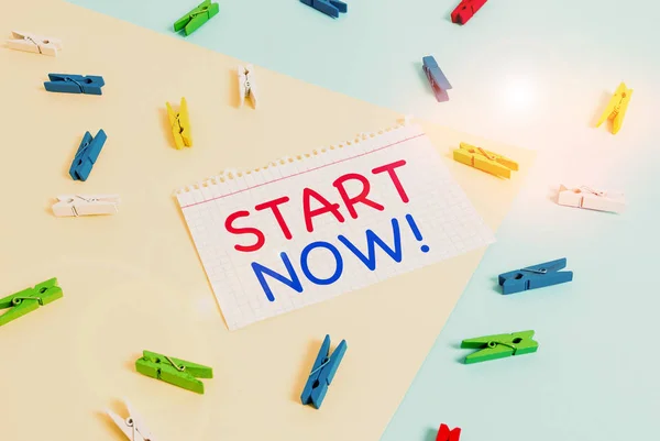 Handwriting text Start Now. Concept meaning do not hesitate get working or doing stuff right away Colored clothespin paper empty reminder yellow blue floor background office.