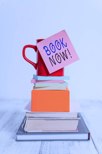 Концептуальный почерк, показывающий Book Now. Бизнес фото демонстрации гарантированно есть место, потому что вы уже купили его Кубок липкие записки сложены блокноты книги коробки деревянный стол
.