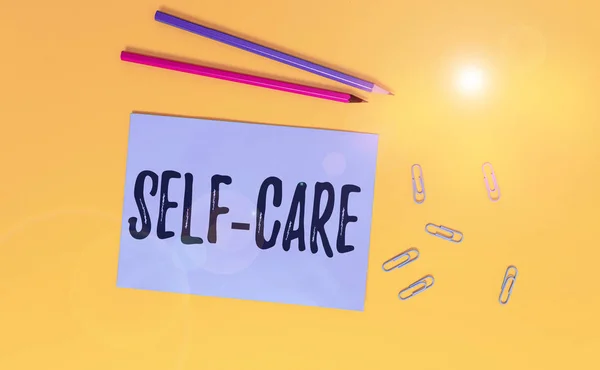 Conceptual hand writing showing Self Care. Business photo text the practice of taking action to improve one s is own health Blank paper sheet message reminder pencils clip colored background. — Stock Photo, Image