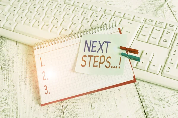 Handwriting text Next Steps. Concept meaning something you do after you have finished doing first one notebook paper reminder clothespin pinned sheet white keyboard light wooden.