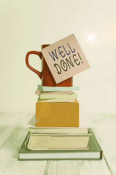 Conceptual hand writing showing Well Done. Business photo showcasing used praising demonstrating or group for something have done good way Cup sticky note stacked note pads books box wooden table.