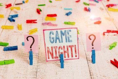 Game Night 'ı gösteren bir not yazıyorum. İş fotoğraflarının sergilenmesi genelde poker gibi yetişkinlerin oyun buluşmalarında olur. Arkadaşları tahta masaya raptiyeli çarşaf kırarlar..
