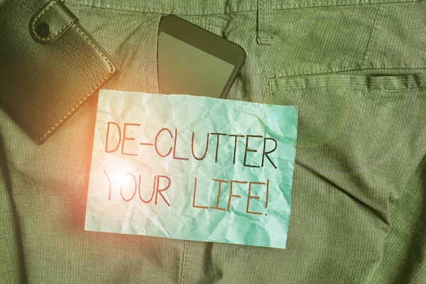 De Clutter Your Lifeを示すテキストサイン。概念的な写真は、整理されていないまたは混雑していない場所から不要なアイテムを削除します財布やメモ用紙とズボンのフロントポケット内のスマートフォンデバイス. — ストック写真