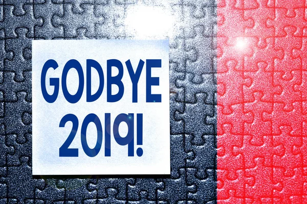 Handwriting text Godbye 2019. Concept meaning express good wishes when parting or at the end of last year Piece of square note paper use for give notation stick to puzzle background.