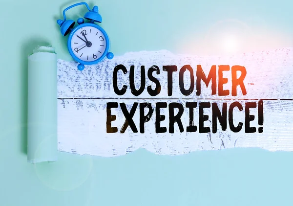 Writing note showing Customer Experience. Business photo showcasing product of interaction between organization and buyer Alarm clock and torn cardboard on a wooden classic table backdrop. — Stock Photo, Image