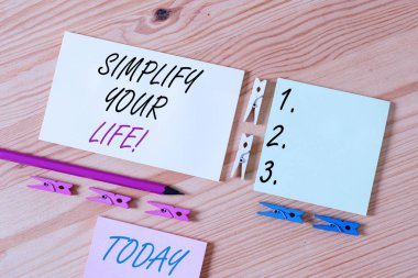 Kelime yazma metni Hayatınızı Basitleştirin. Önemli odaklanmış ve başkasının daha az olanlar hakkında endişelenmesine izin İş konsepti Renkli clothespin kağıtları boş hatırlatma ahşap zemin arka plan ofis.