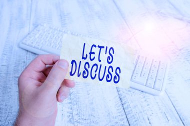 Let S Discuss 'u gösteren metin işareti. Kavramsal fotoğraf, birinden elinde renkli hatırlatıcı kare şeklindeki kağıt beyaz klavye ahşap zemin tutan bir adam hakkında konuşmasını istiyor..