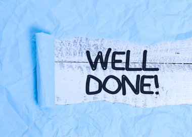 Text sign showing Well Done. Conceptual photo used praising demonstrating or group for something have done good way Cardboard which is torn in the middle placed above a wooden classic table.
