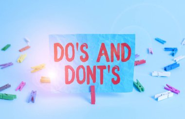 Do S ve Don 't S. iş fotoğraflarının bazı aktivite ve eylemlerle ilgili kural ve gelenekleri gösterdiğini gösteren bir not. Renkli çamaşır tokası dikdörtgeni şekilli kağıt açık mavi arkaplan.