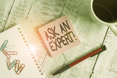 Ask An Expert 'ı gösteren bir not yazıyorum. İş fotoğraflarının doğrulanması, ahşap masanın üzerinde duran bir fincan sade kahvenin yanına koyulan talimatları anladığını ve onayladığını gösteriyor..