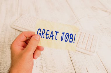 Harika bir iş çıkardığını gösteren bir mesaj. Kavramsal fotoğraf, yaptığı bir şey için birini övmek için kullanılıyor. Renkli, kare şeklinde kağıt, klavye şeklinde ahşap zemin tutan iyi bir adam..