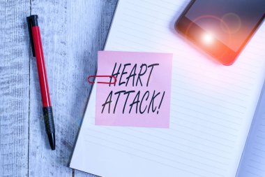 Kalp Saldırısı 'nı yazan el yazısı. Konsept, ölüm ile sonuçlanan koroner trombozun ani oluşumu anlamına gelir. Kalın sayfalar, klasik ahşap zemin üzerine yerleştirilmiş defter..