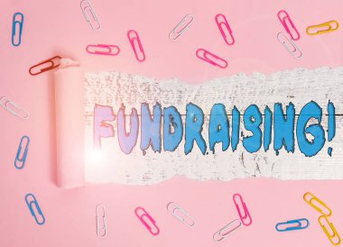 Conceptual hand writing showing Fundraising. Business photo showcasing seeking to generate financial support for charity or cause Paper clip and torn cardboard on wood classic table backdrop. clipart