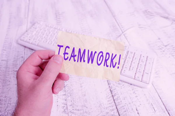 Text sign showing Teamwork. Conceptual photo combined action of group especially when effective and efficient man holding colorful reminder square shaped paper white keyboard wood floor. — 스톡 사진