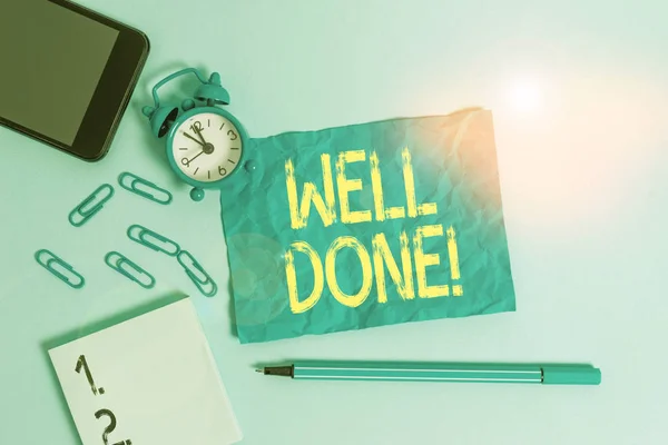 Text sign showing Well Done. Conceptual photo used praising demonstrating or group for something have done good way Alarm clock clips notepad smartphone sheet marker colored background.
