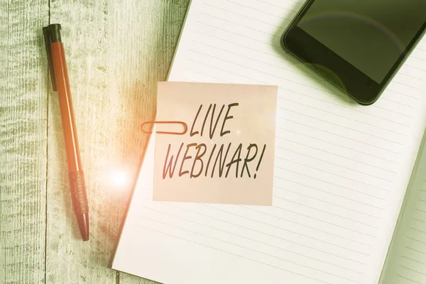 Handwriting text writing Live Webinar. Concept meaning presentation lecture or seminar transmitted over Web Thick pages notebook stationary placed above classic look wooden backdrop.