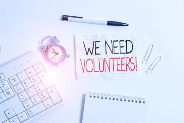 Conceptual hand writing showing We Need Volunteers. Business photo showcasing someone who does work without being paid for it Copy space on note paper with clock and pencil on the table. — ストック写真