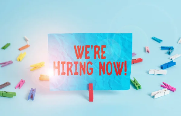 Writing note showing We Re Hiring Now. Business photo showcasing recently employ someone or pay someone to do particular job Colored clothespin rectangle square shaped paper light blue background. — 图库照片