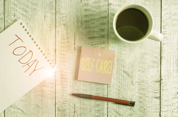 Writing note showing Self Care. Business photo showcasing practice of taking action to preserve or improve ones own health Stationary placed next to a cup of black coffee above the wooden table. — Stock Photo, Image