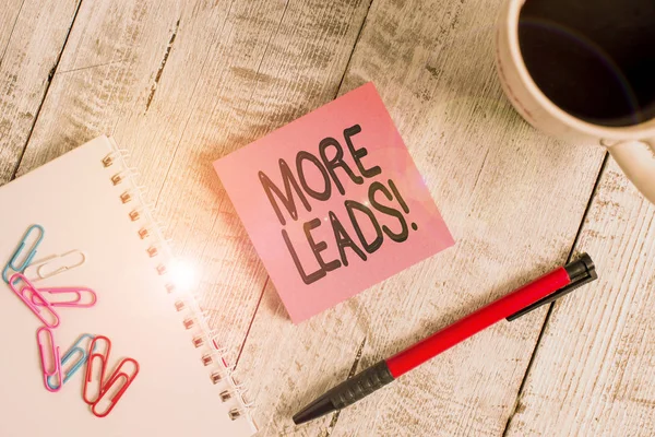 Writing note showing More Leads. Business photo showcasing initiation of consumer interest or enquiry into product Stationary placed next to a cup of black coffee above the wooden table.