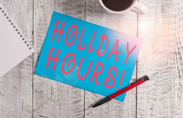 Text sign showing Holiday Hours. Conceptual photo Overtime work on for employees under flexible work schedules Stationary placed next to a cup of black coffee above the wooden table.