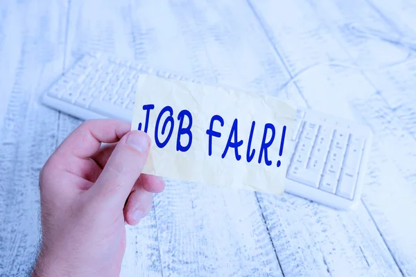 Sinal de texto mostrando Job Fair. Evento de foto conceitual em que os empregadores recrutadores dão informações aos funcionários homem segurando lembrete colorido quadrado em forma de papel branco teclado piso de madeira . — Fotografia de Stock