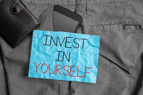 显示在你自己身上投资的文字符号。概念性的照片学习新的东西或材料，从而使你的很多更好的智能手机装置在裤子前袋与钱包和便条纸. — 图库照片