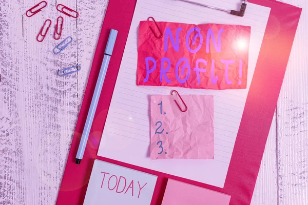 Text sign showing Non Profit. Conceptual photo not making or conducted primarily to make profit organization Clipboard sheet crushed sticky note clip notepads marker wooden background.