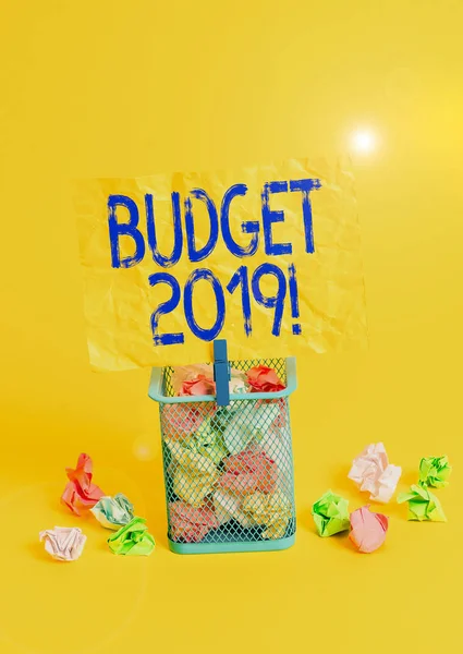 Conceptual hand writing showing Budget 2019. Business photo text estimate of income and expenditure for current year Trash bin crumpled paper clothespin office supplies yellow.